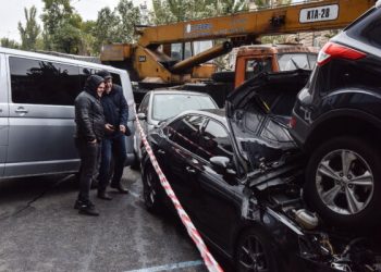 People look at crashed cars at site of a road traffic accident after a mobile crane crashed into passenger vehicles on Oct. 22, 2018, in Kyiv.