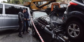 People look at crashed cars at site of a road traffic accident after a mobile crane crashed into passenger vehicles on Oct. 22, 2018, in Kyiv.