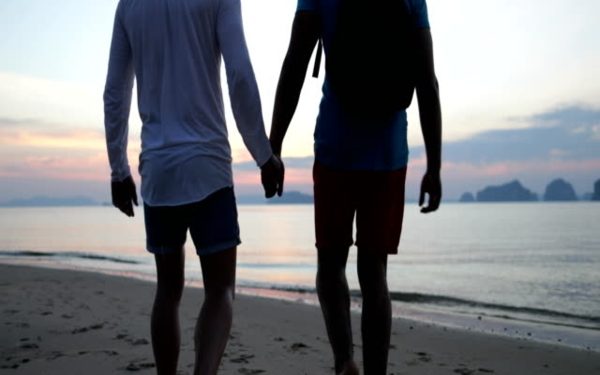 Gay Couple Walk On Beach At Sunset Holding Hands, Back Rear View Two Man Slow Motion 60
