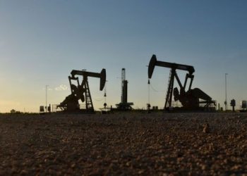 FILE PHOTO: Pump jacks operate in front of a drilling rig in an oil field in Midland, Texas U.S. August 22, 2018. Picture taken August 22, 2018. REUTERS/Nick Oxford/File Photo