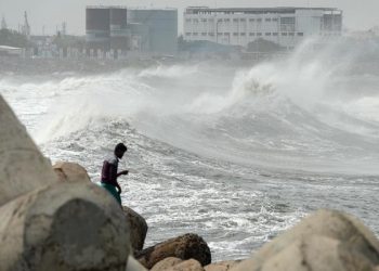 A man looks out as waves hit a breakwater at Kasimedu fishing harbour in Chennai on May 19, 2020, as Cyclone Amphan barrels towards India's eastern coast. (Photo by Arun SANKAR / AFP)