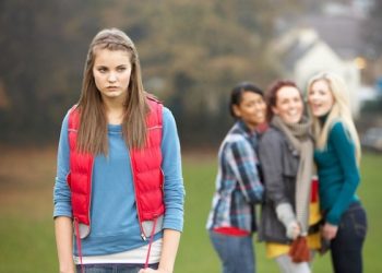 Upset Teenage Girl With Friends Gossiping In Background
