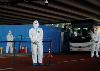 Staff members in protective suits stand guard next to a bus before the expected arrival of a World Health Organisation (WHO) team tasked with investigating the origins of the coronavirus disease (COVID-19) pandemic, at Wuhan Tianhe International Airport in Wuhan, Hubei province, China January 14, 2021. REUTERS/Thomas Peter
