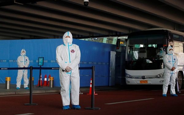 Staff members in protective suits stand guard next to a bus before the expected arrival of a World Health Organisation (WHO) team tasked with investigating the origins of the coronavirus disease (COVID-19) pandemic, at Wuhan Tianhe International Airport in Wuhan, Hubei province, China January 14, 2021. REUTERS/Thomas Peter