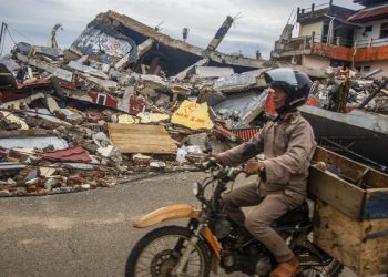 epaselect epa08942953 A man rides his motorbike past collapsed houses in the aftermath of an earthquake in Mamuju, West Sulawesi, Indonesia, 17 January 2021. At least 56 people were killed and hundreds injured after a 6.2 magnitude earthquake struck Sulawesi island on 15 January.  EPA-EFE/IQBAL LUBIS