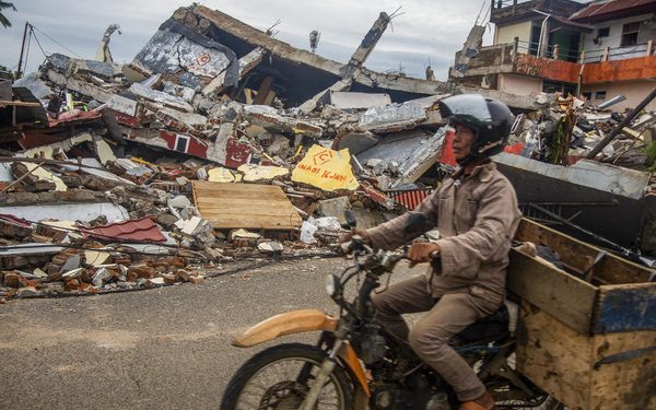 epaselect epa08942953 A man rides his motorbike past collapsed houses in the aftermath of an earthquake in Mamuju, West Sulawesi, Indonesia, 17 January 2021. At least 56 people were killed and hundreds injured after a 6.2 magnitude earthquake struck Sulawesi island on 15 January.  EPA-EFE/IQBAL LUBIS