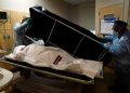 FILE - In this Jan. 9, 2021 file photo, transporters Miguel Lopez, right, Noe Meza prepare to move a body of a COVID-19 victim to a morgue at Providence Holy Cross Medical Center in the Mission Hills section of Los Angeles. Just a little more than a year after California announced its first case of coronavirus, the nation's most populous state is on the brink of recording its 40,000th death. (AP Photo/Jae C. Hong, File)