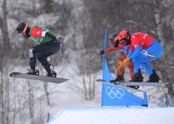 epa09748459 Nick Baumgartner of the USA (left) leads Eliot Grondin of Canada and Omar Visintin of Italy (right) at the final jump in the big final during the Mixed Team Snowboard Cross at the Genting Snow Park, during the 2022 Beijing Winter Olympic Games, in Beijing, China,  12 February 2022.  EPA-EFE/DAN HIMBRECHTS  AUSTRALIA AND NEW ZEALAND OUT