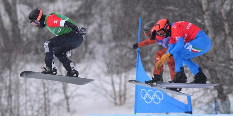 epa09748459 Nick Baumgartner of the USA (left) leads Eliot Grondin of Canada and Omar Visintin of Italy (right) at the final jump in the big final during the Mixed Team Snowboard Cross at the Genting Snow Park, during the 2022 Beijing Winter Olympic Games, in Beijing, China,  12 February 2022.  EPA-EFE/DAN HIMBRECHTS  AUSTRALIA AND NEW ZEALAND OUT