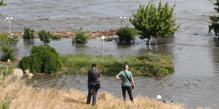 Локални жители гледаат во делумно поплавената област Керсон на 6 јуни 2023 година, по штетата претрпена на браната на ХЕ Каховка (Photo: AFP)