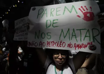 Активист покажува транспарентн на кој пишува на португалски „Престанете да не убивате. Не за нафтата во Амазон“