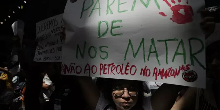 Активист покажува транспарентн на кој пишува на португалски „Престанете да не убивате. Не за нафтата во Амазон“